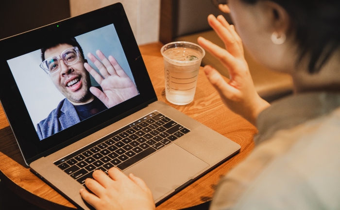 Man with glasses on a video conference call, waving hello to an interviewer