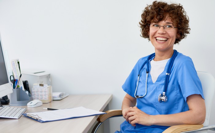 A smiling nurse practitioner sitting at her desk 