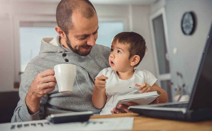 Father drinks coffee while holding his young child and using our online learning tips.
