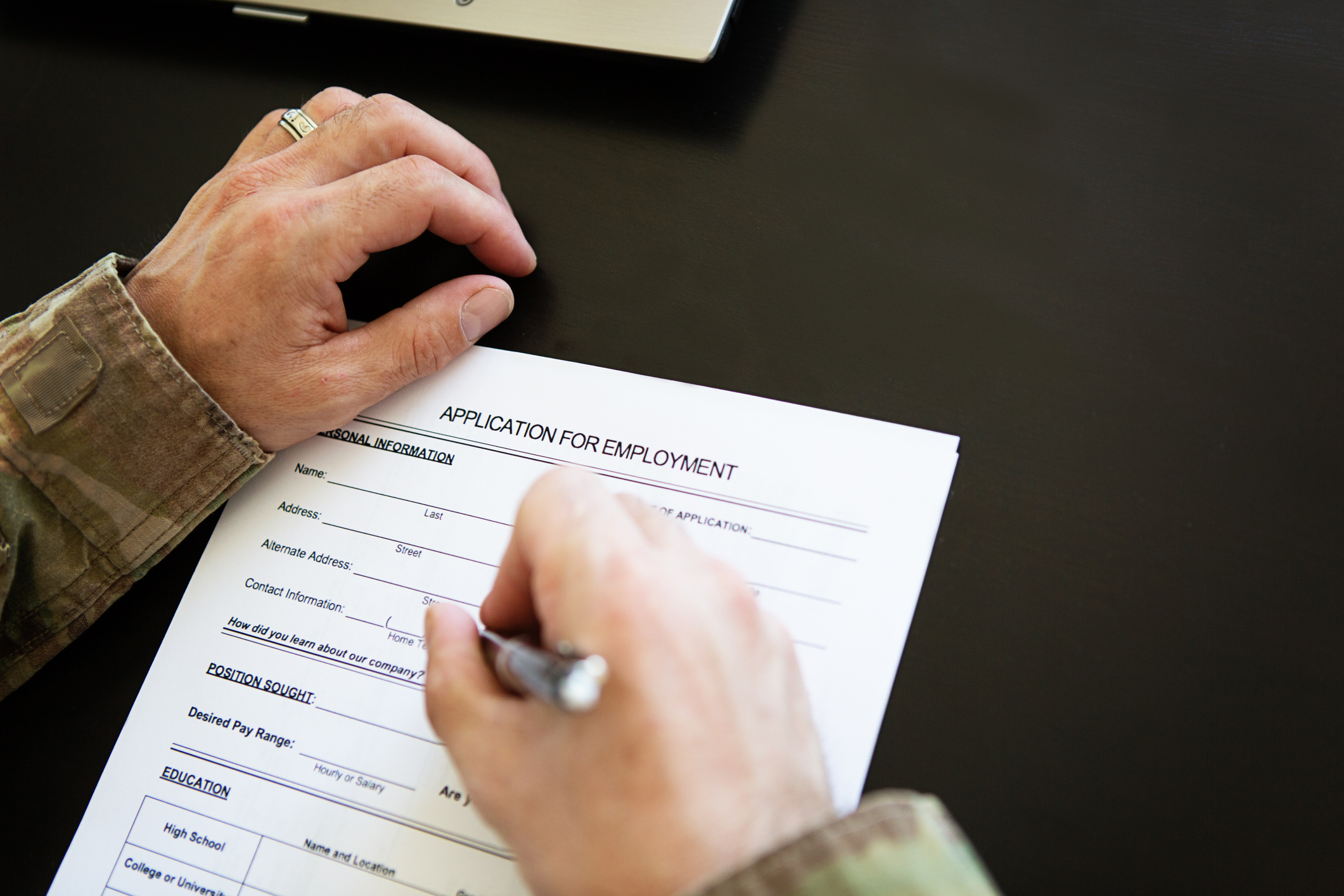 New research from the College of Health Sciences demonstrates that employment is key to veteran's social and emotional wellbeing. Photo description: A veteran in uniform fills out an employment application. 